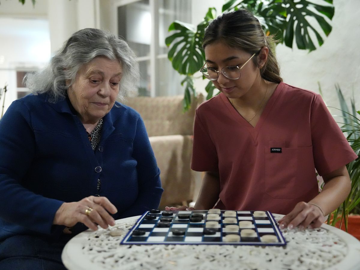 A resident and carer playing checkers together